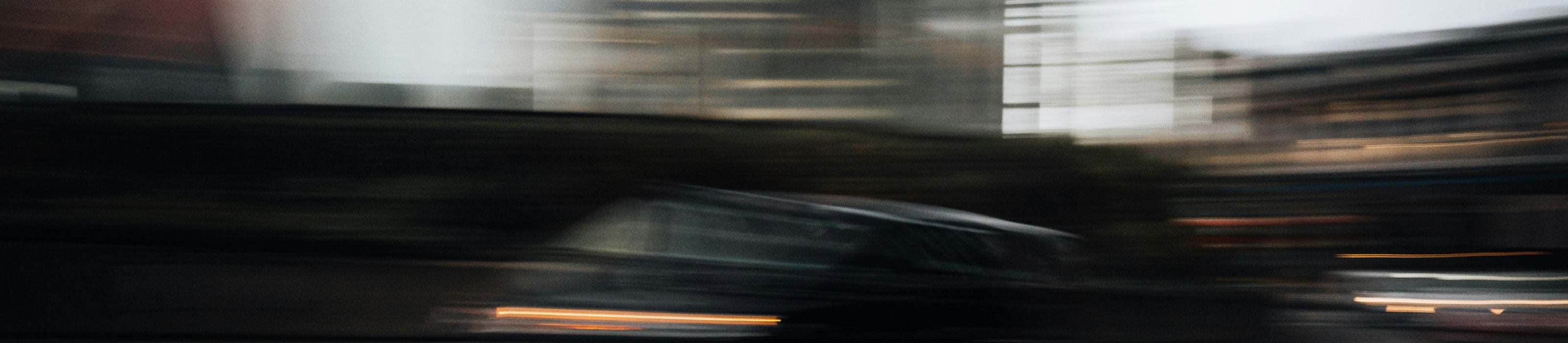 Blurred image of a car on a road with buildings in the background