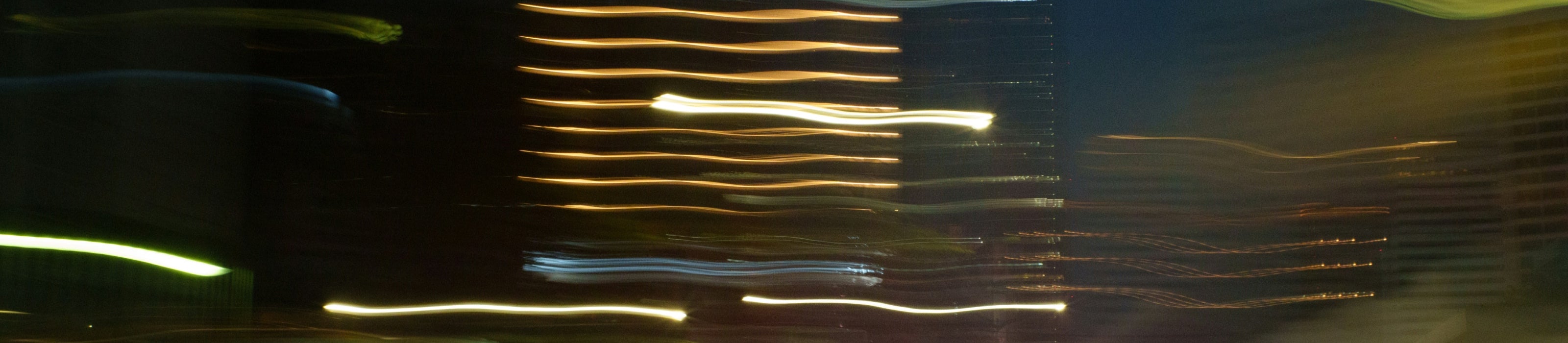 Long exposure of light streaks coming from buildings in a dark setting