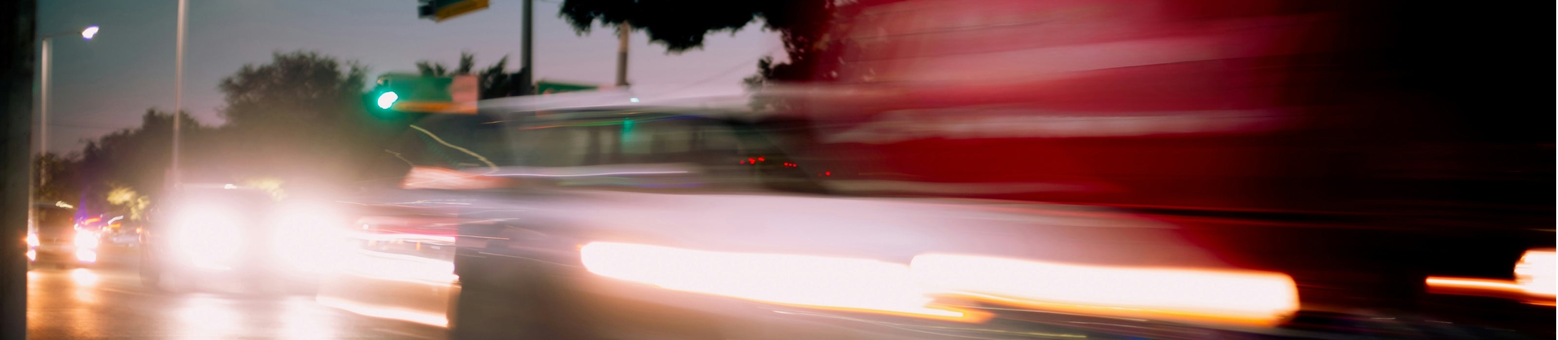 Blurred motion of a car on a city street at night with lights and traffic.